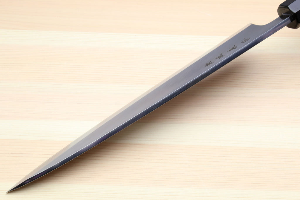 Japanese fish filet knife with dark handle and long silver blade, diagonal close-up