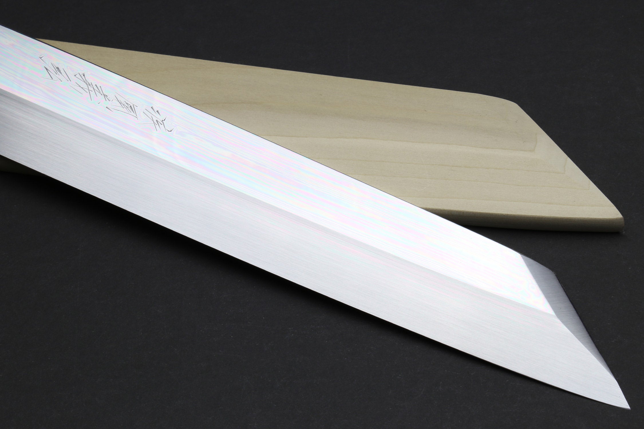 Kiritsuke knife blade close-up with mirror-finished steel edge and iridescent sheen