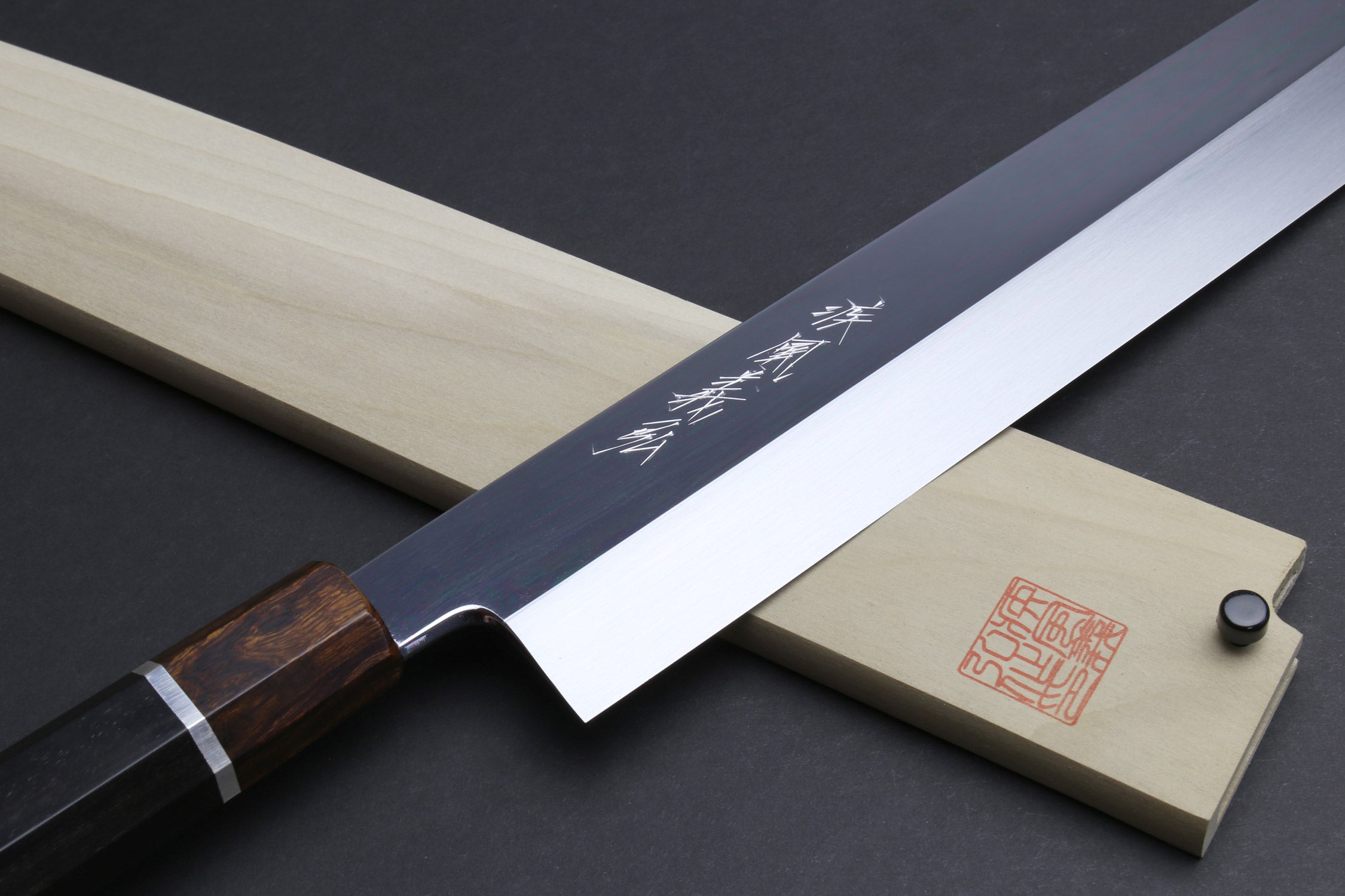 Japanese kiritsuke knife with mirror-finished blade, dark handle, and silver ring at bolster