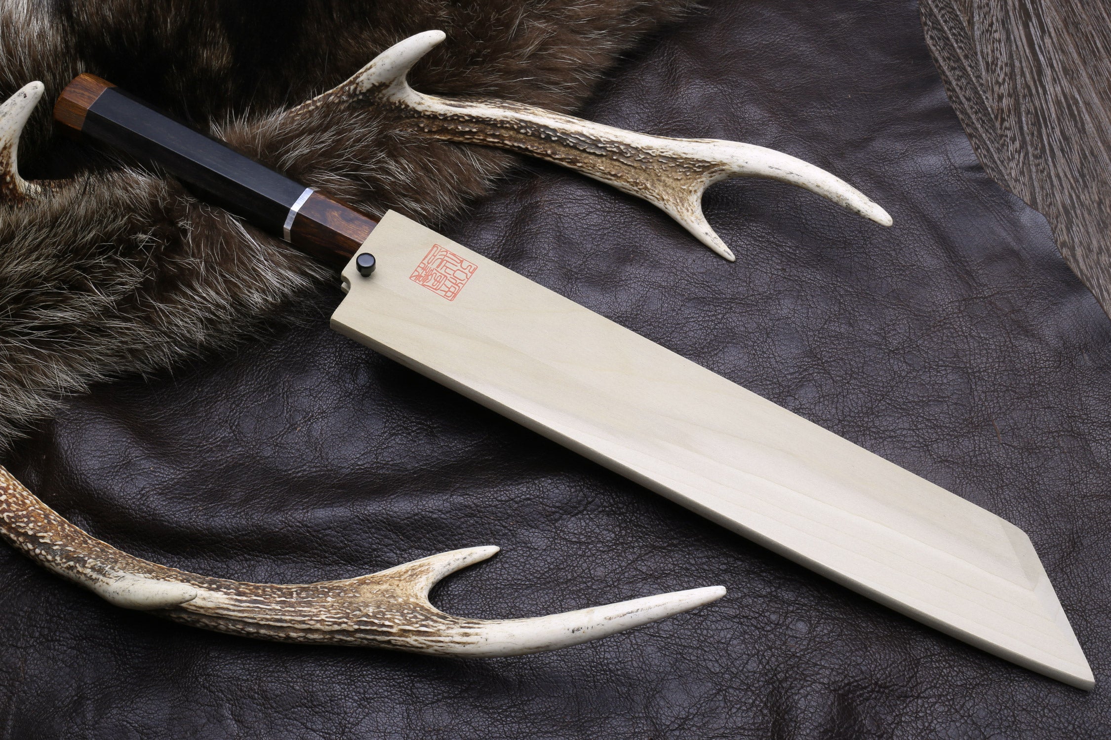 Japanese kiritsuke knife with mirror-finished blade, dark wood handle, and silver ring