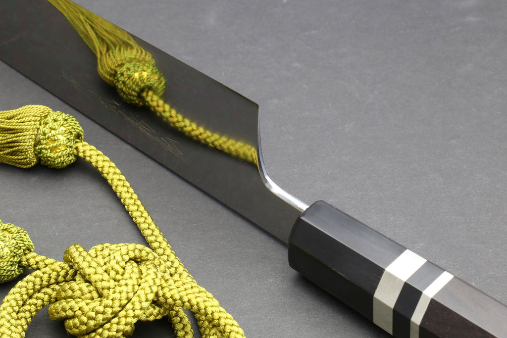 Gyuto chef knife side view with mirror blade and ebony handle with striped grip accents