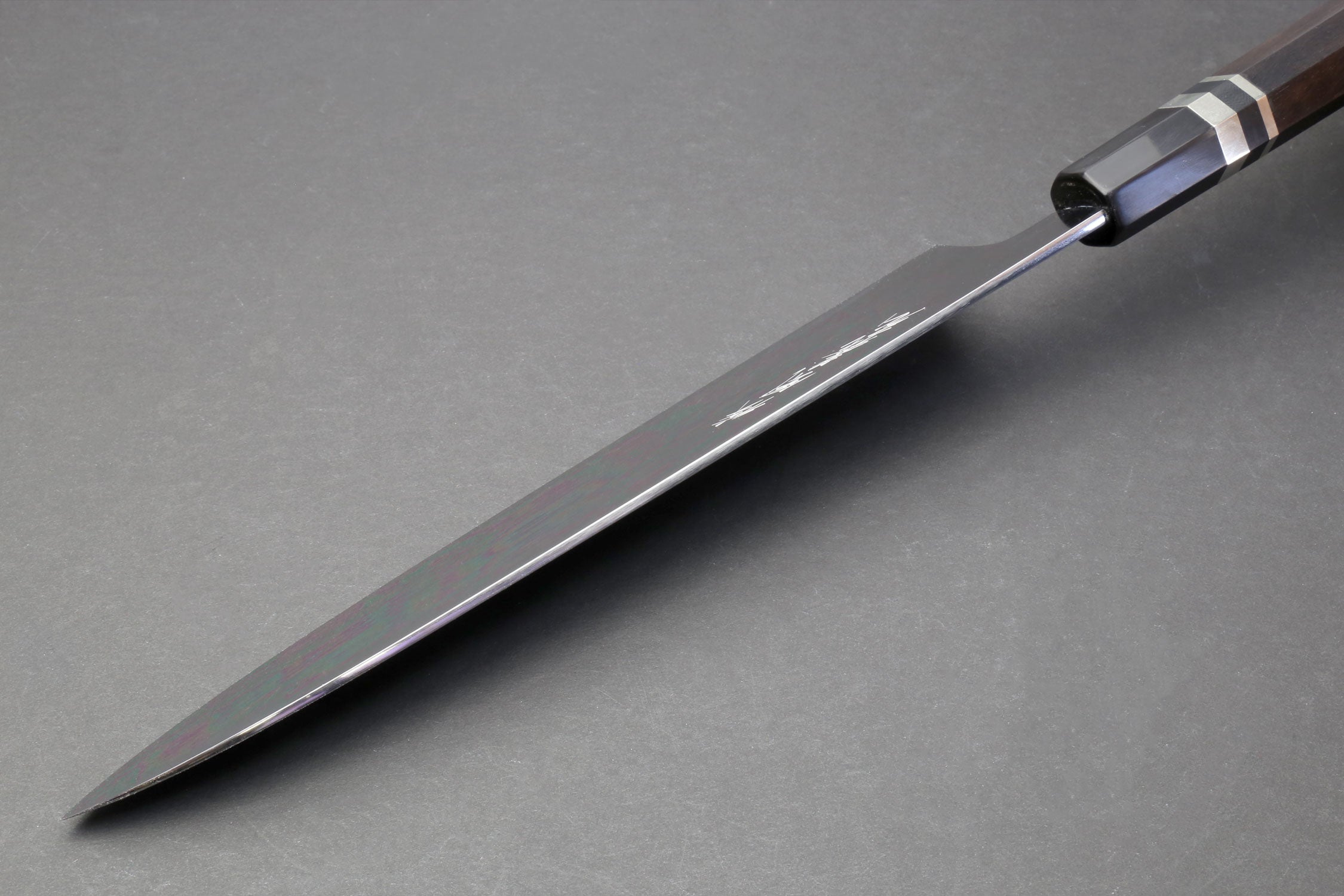 Gyuto chef knife angled view with mirror blade tip and dark ebony handle