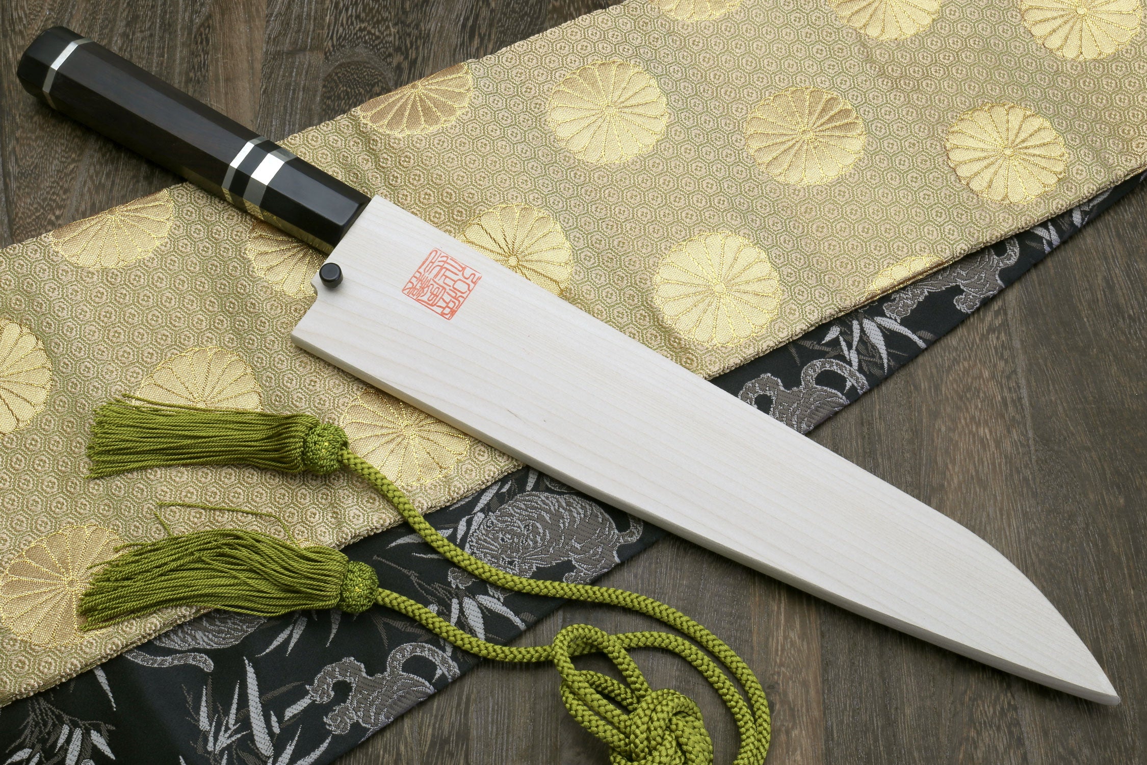 Wa gyuto chef knife: mirror-polished steel blade, ebony handle, green cord tassel.