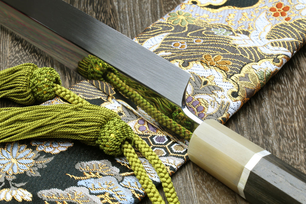 Japanese katana blade close-up in sheath, silver finish, light wood fittings.