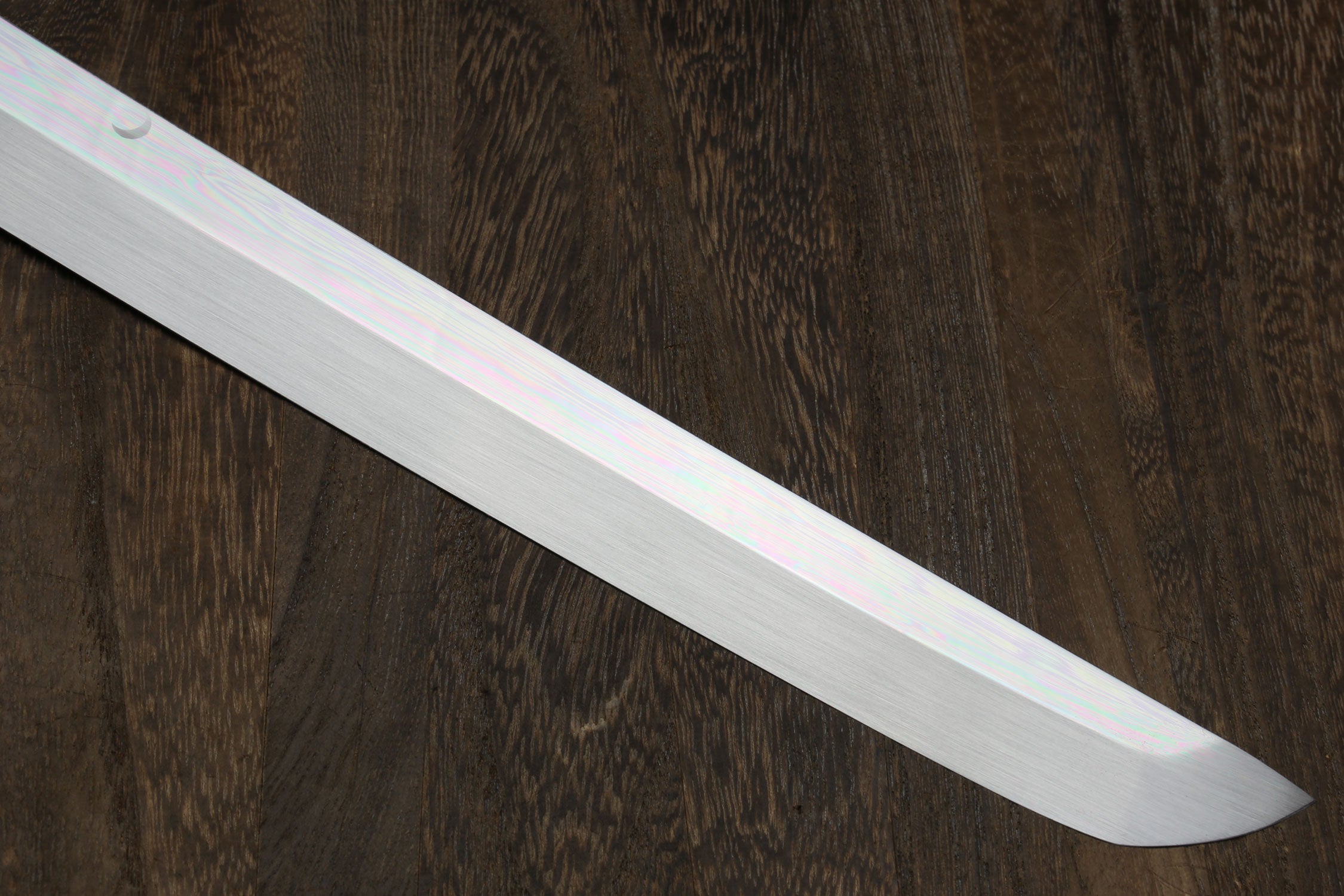 Mirror-finished silver katana blade close-up, straight tip.