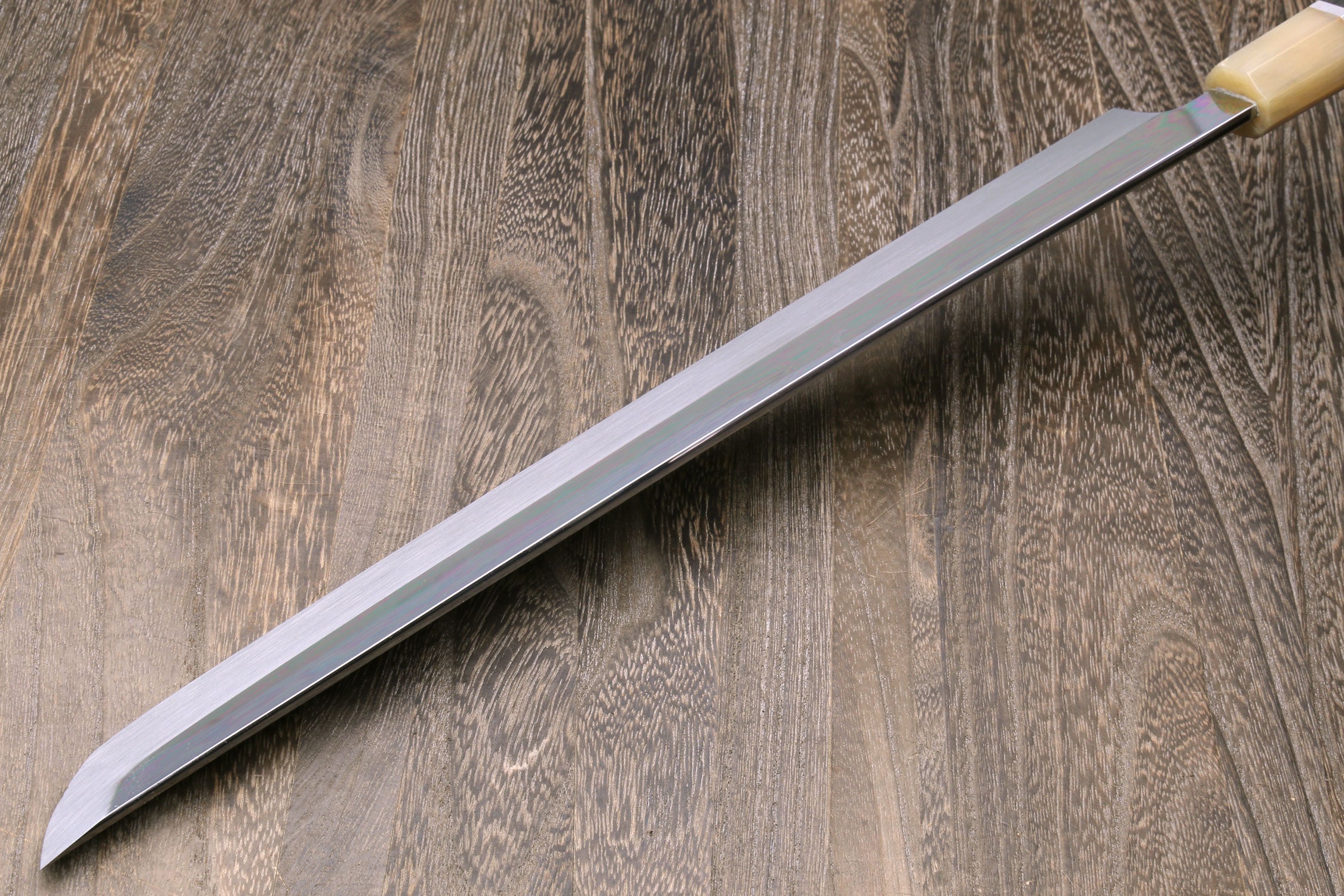 Japanese katana blade close-up, silver finish and light wood handle cap.