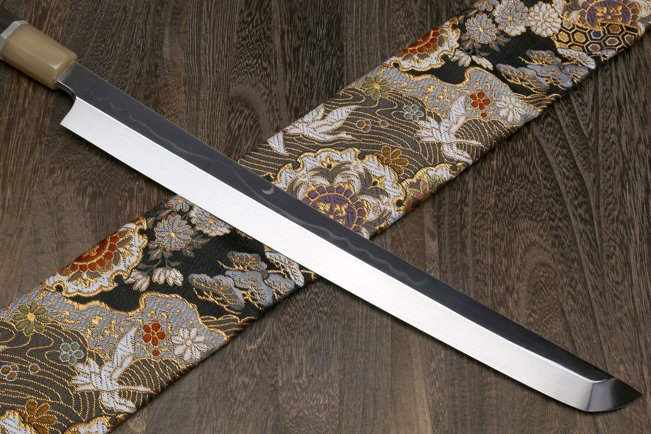 Japanese katana sword with silver blade and ornate patterned wrap, light handle caps.