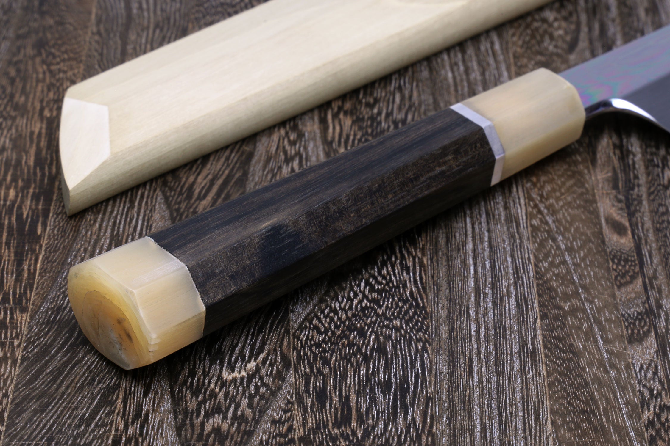 Japanese katana sword with dark handle and silver guard, light wood fittings.