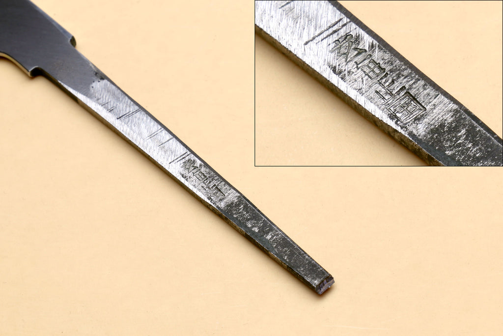 Japanese katana blade close-up with etched marks and brushed steel shine.