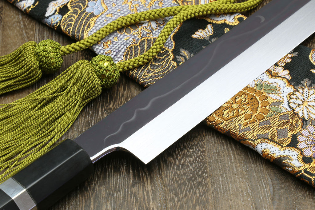 Yanagi kiritsuke knife close-up: mirror blade with ebony handle and silver ring