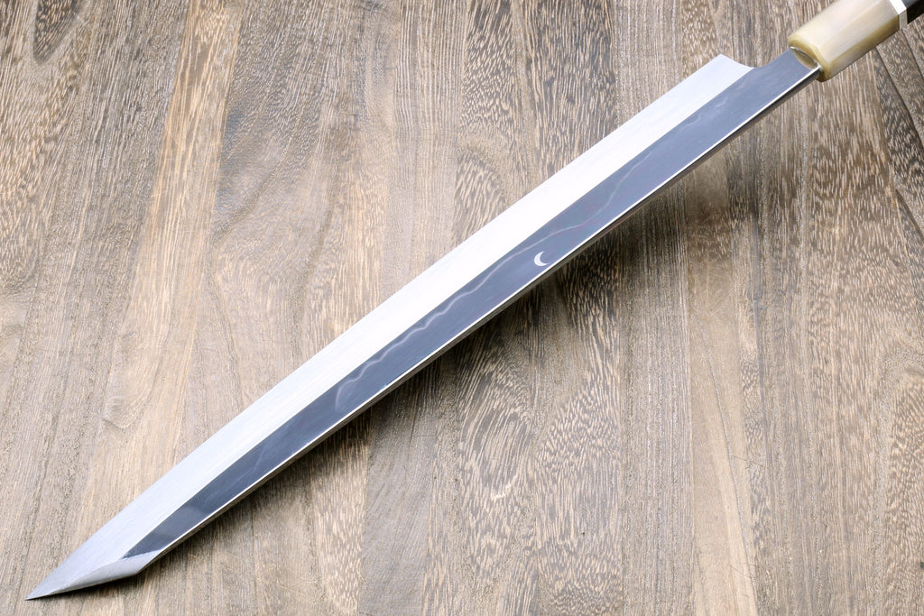Yanagi kiritsuke knife with mirror-finished blade and dark handle with metallic trim