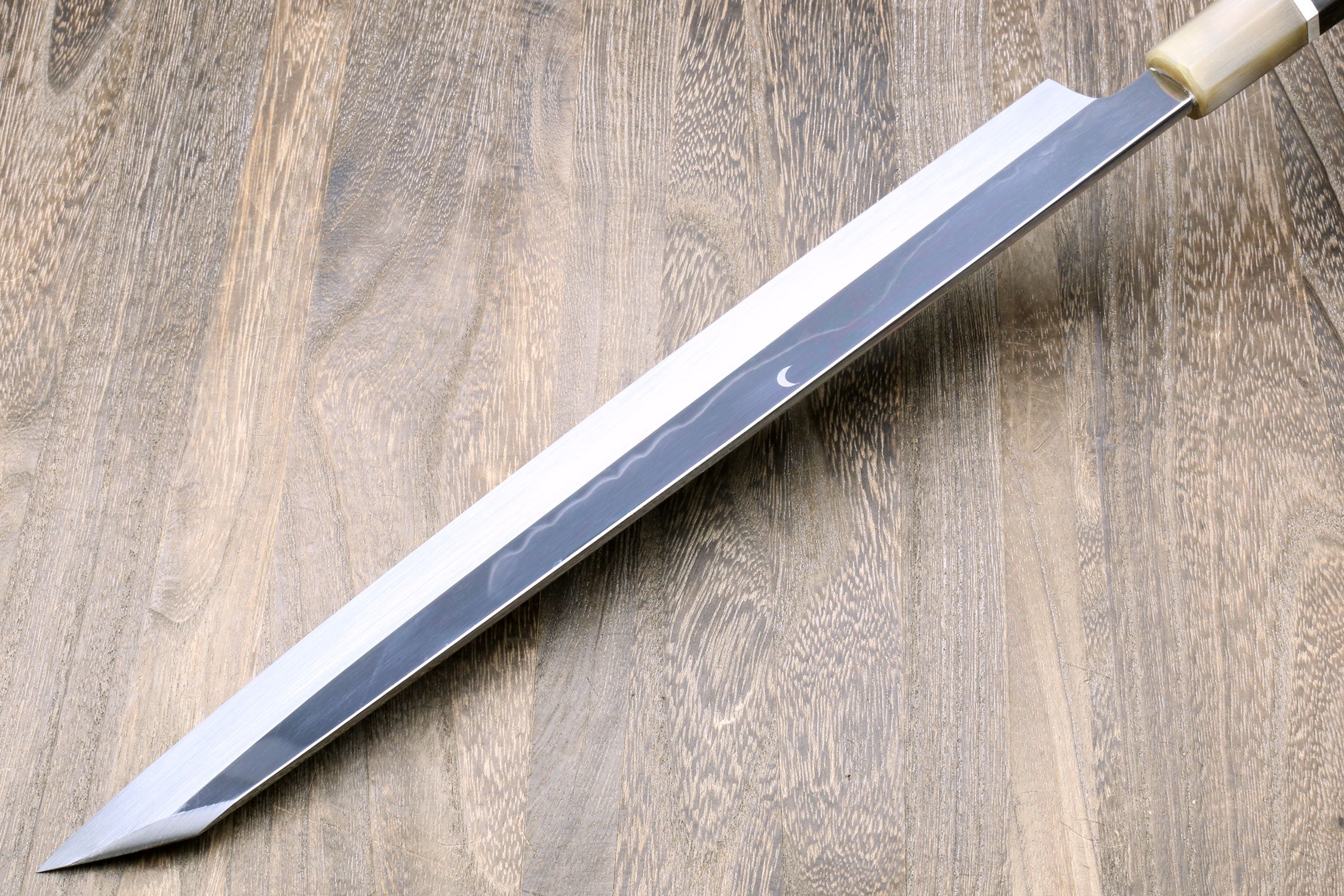 Yanagi kiritsuke knife with mirror-finished blade and dark handle with metallic trim