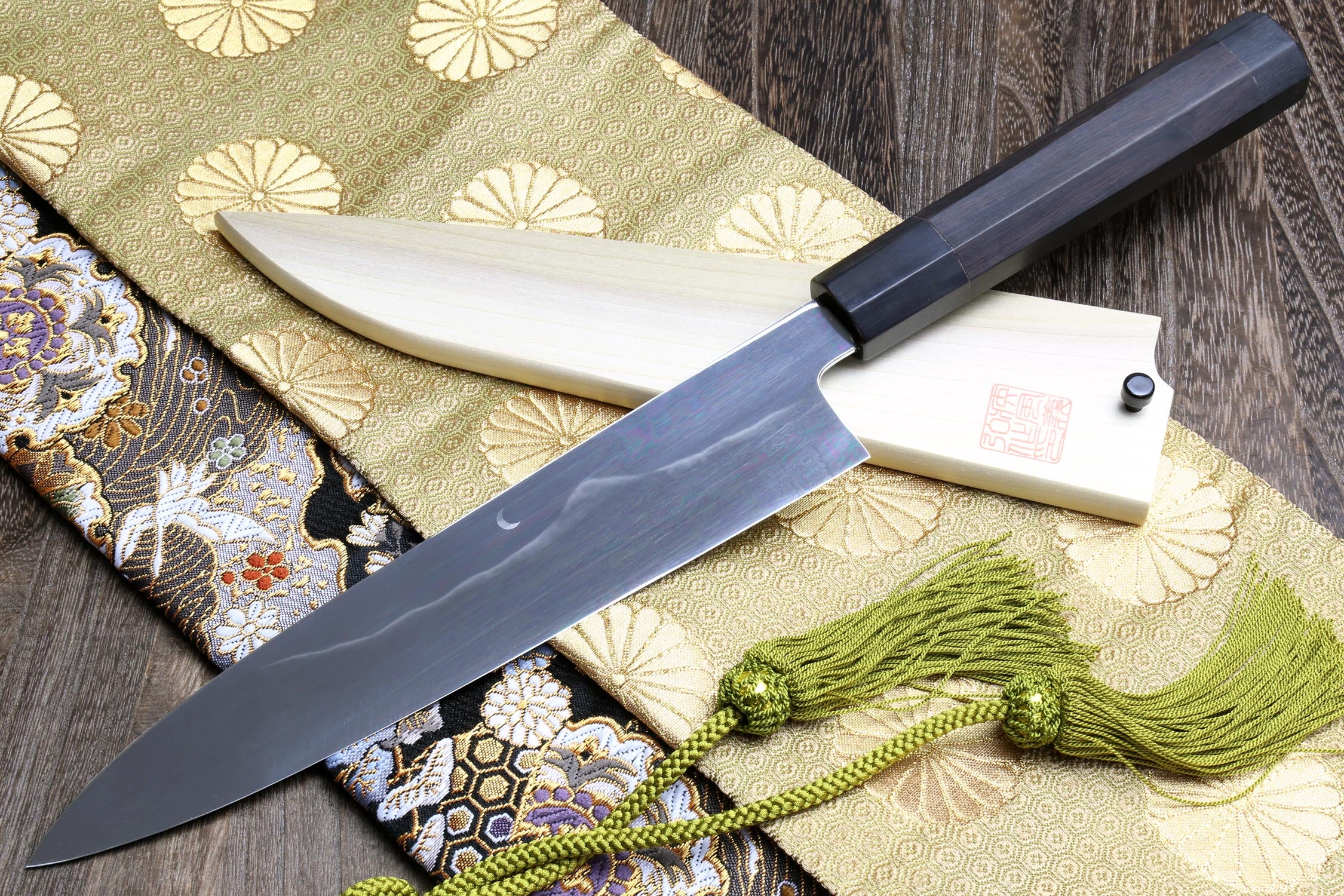 Gyuto chef knife with dark steel blade, white handle scales, and black end cap