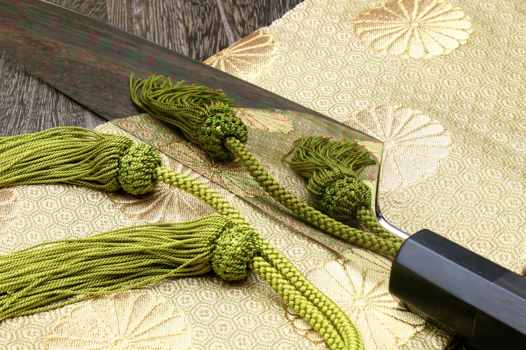 Ebony-handled gyuto chef knife with dark mirror-finished blade and green cord