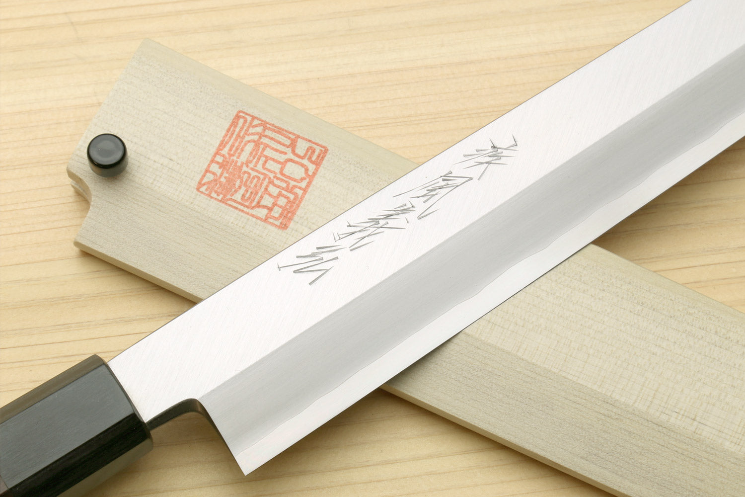 Sushi sashimi knife showing long silver blade with dark spine and rosewood handle