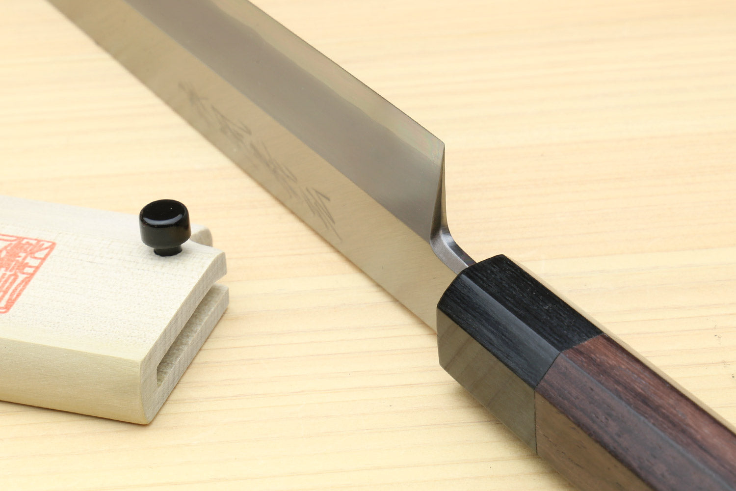 Japanese sushi knife with silver blade, dark rosewood handle, and wooden storage stand