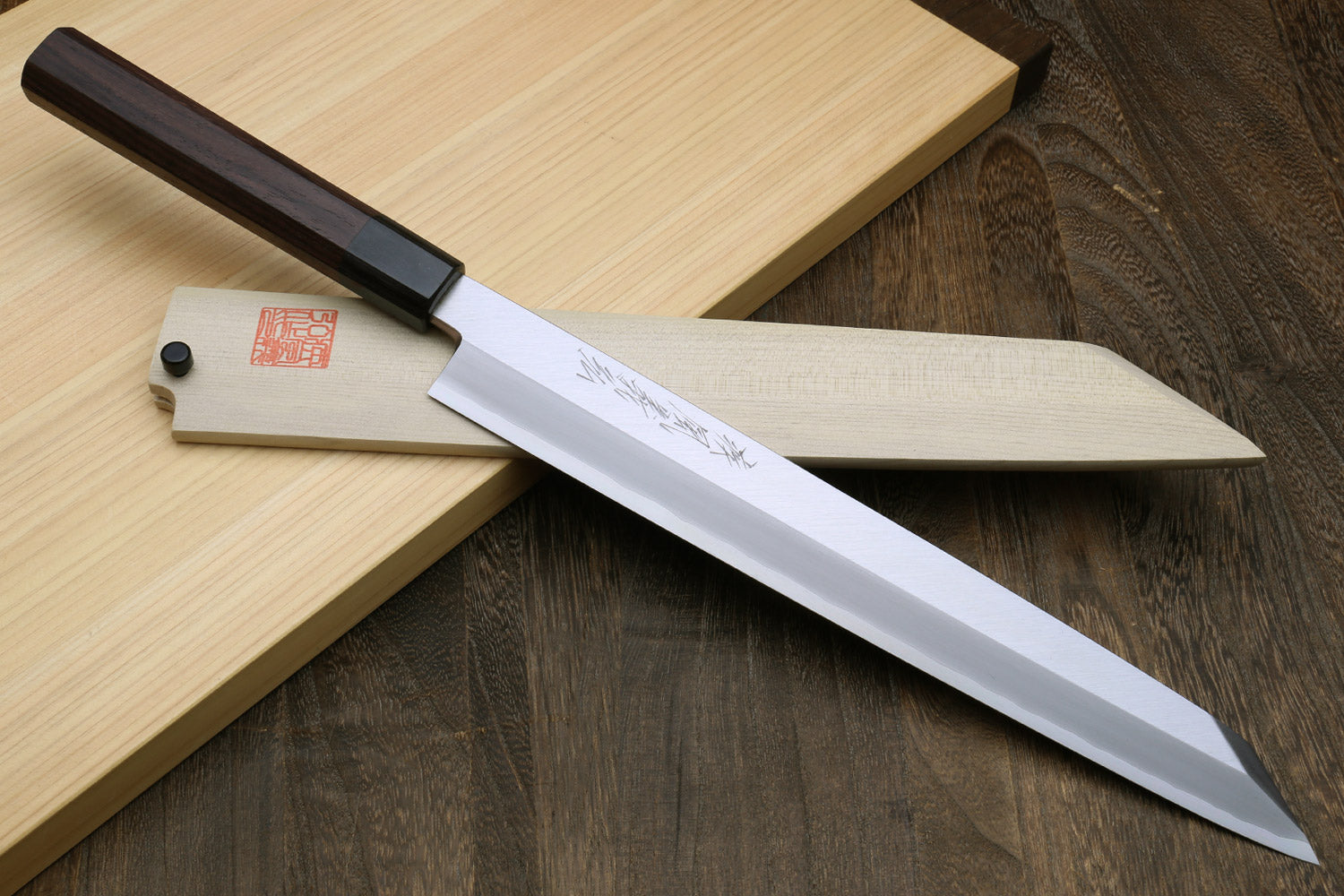 Long sashimi knife with silver stainless blade and dark rosewood handle on wood boards