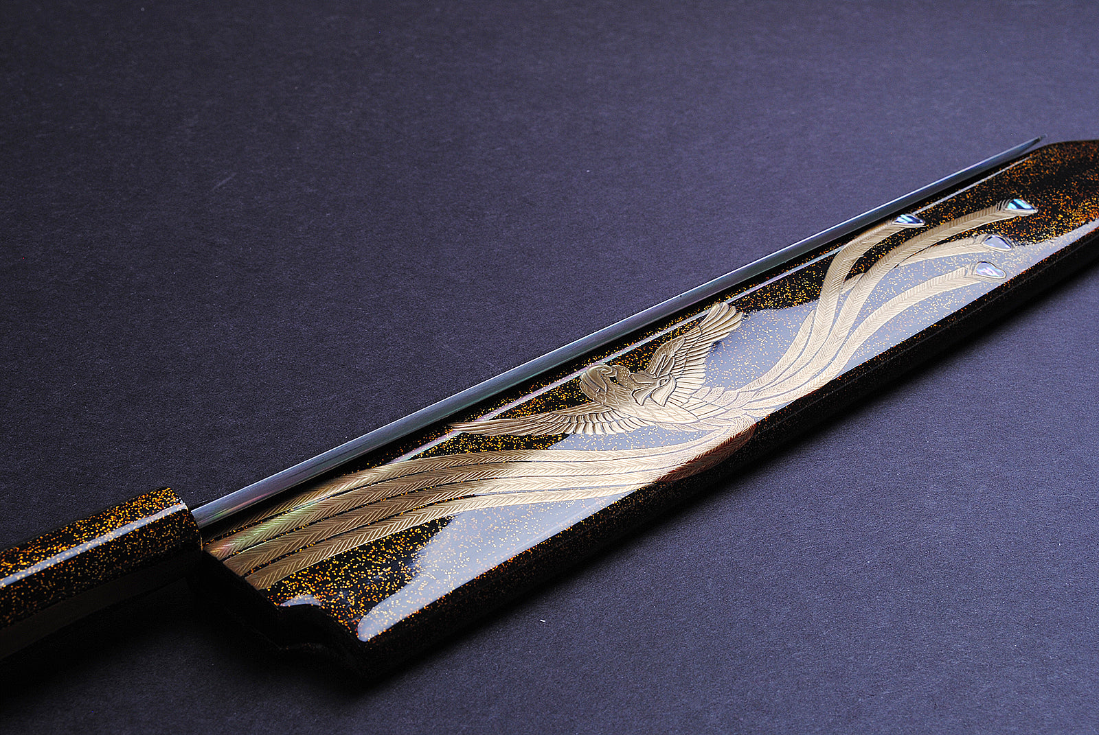 Yanagi kiritsuke knife close-up: gold-and-silver engraving on mirror blade and black handle