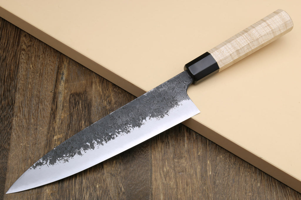 Gyuto chef knife showing white blade edge with nashiji texture and light camphor handle.