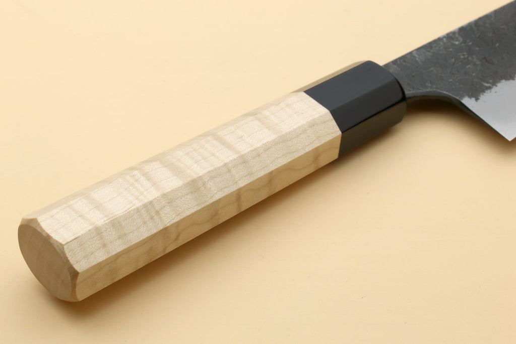 Camphor wood handle with dark bolster and nashiji white steel blade near the heel.