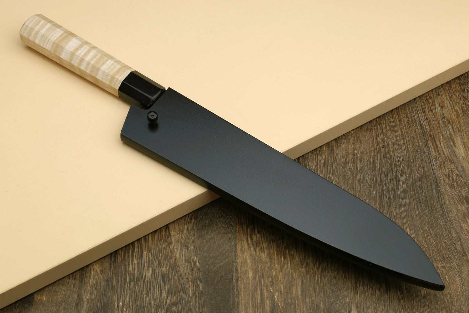 Chef gyuto knife with dark bolster, speckled nashiji white blade, and light camphor handle.