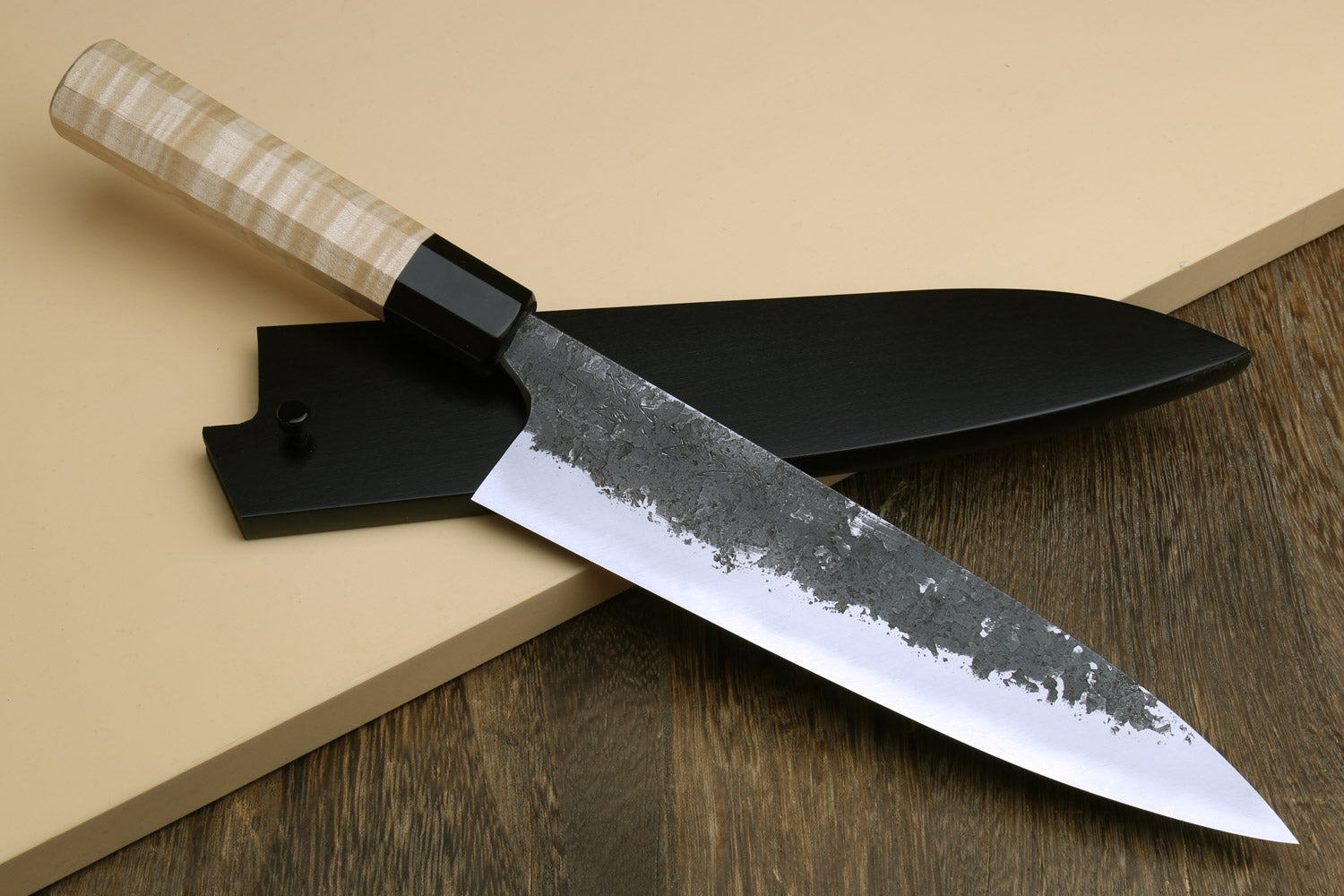 Chef gyuto knife with white steel blade and light camphor wood handle, dark bolster.