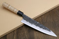 Gyuto chef knife with white nashiji steel blade and light camphor wood handle, dark bolster.