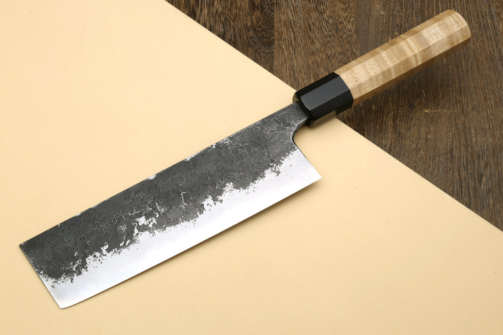 Nakiri knife angled view, dark hammered steel blade with speckled edge, wood handle