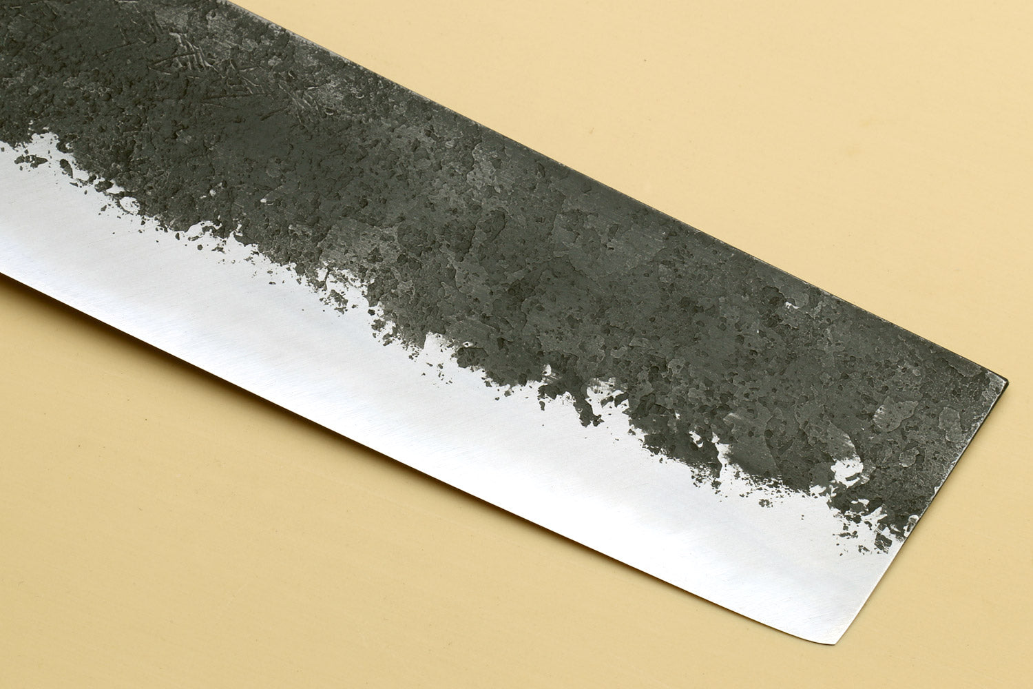Nakiri knife blade side view, dark hammered steel with speckled white edge