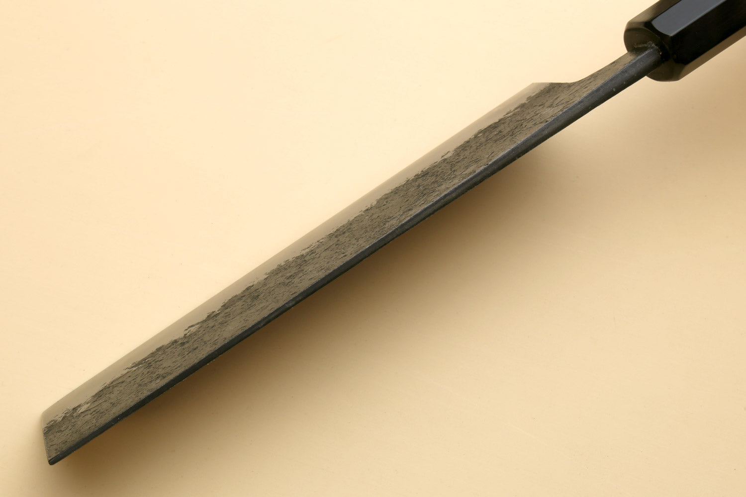 Nakiri knife side view, textured dark steel blade with black spine and wood handle