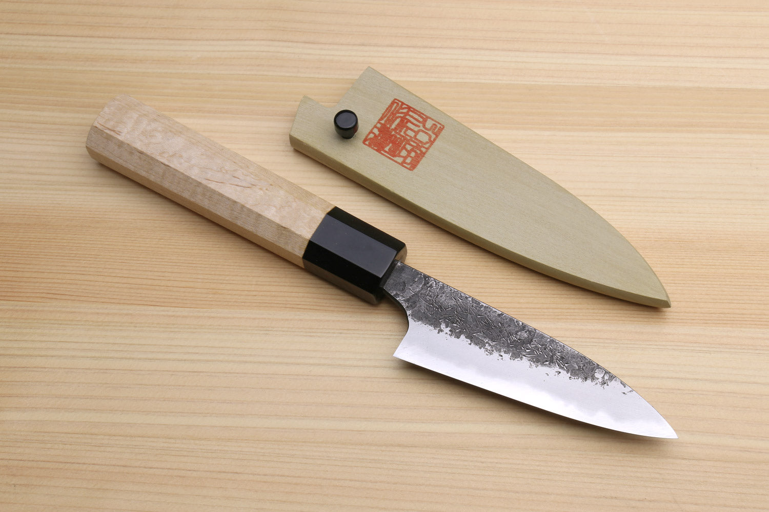 Japanese paring knife with speckled white-steel blade and camphor wood handle, black bolster