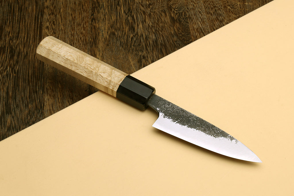 Japanese paring knife showing speckled white-steel blade and camphor wood handle