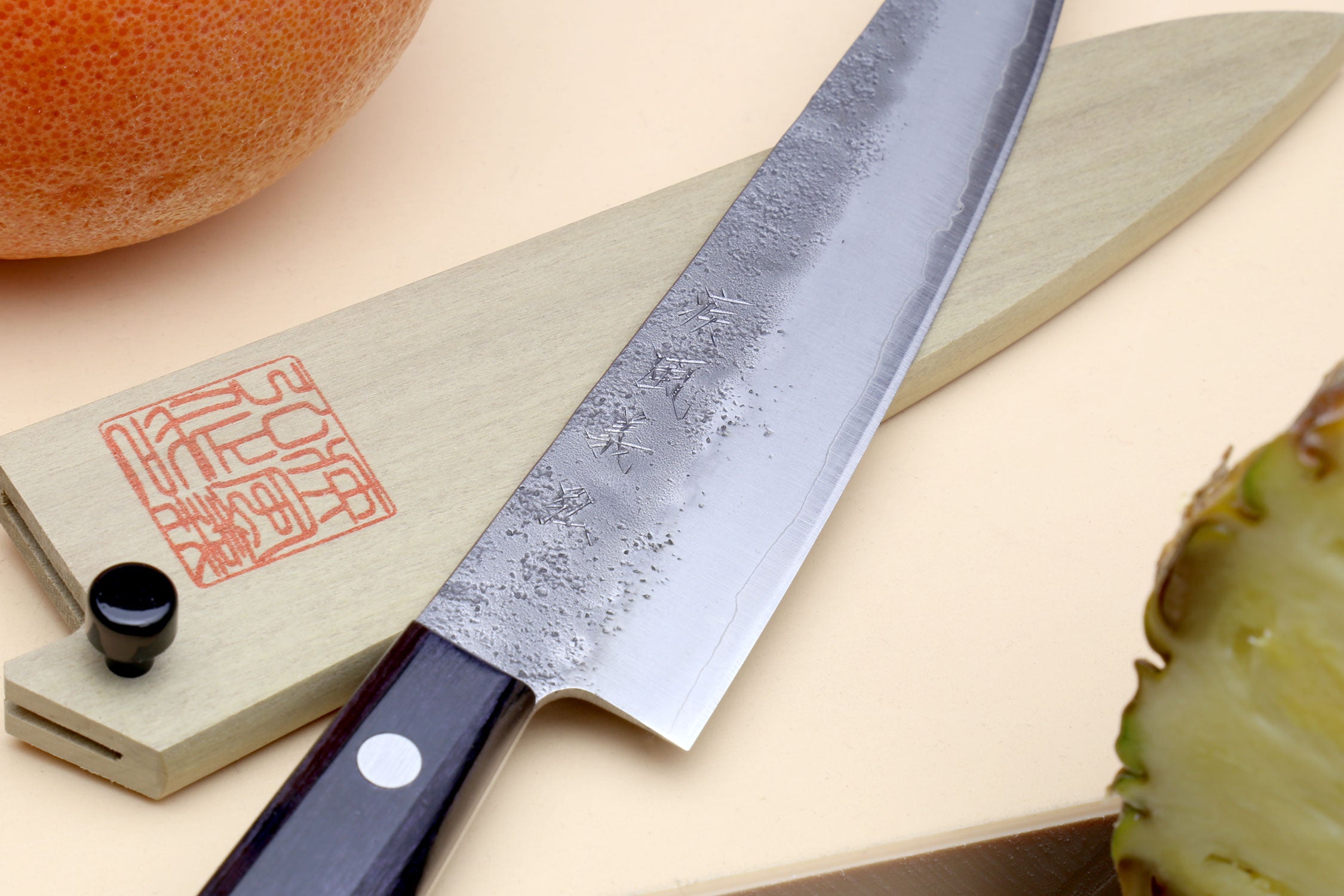 Petty utility knife with dark handle, silver blade, and engraved wooden saya cover