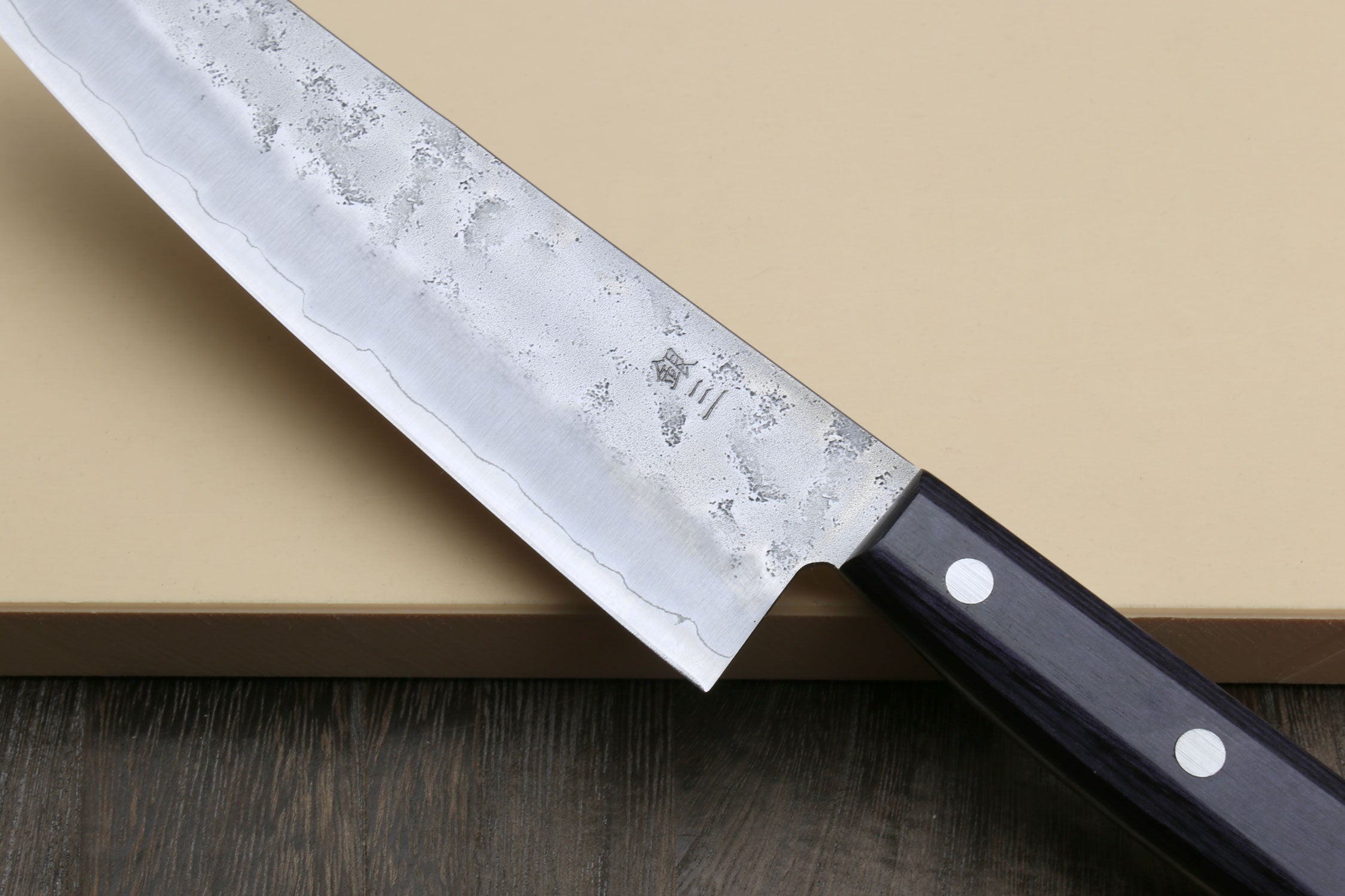 Santoku knife blade close-up at heel, silver finish and dark blue bolster