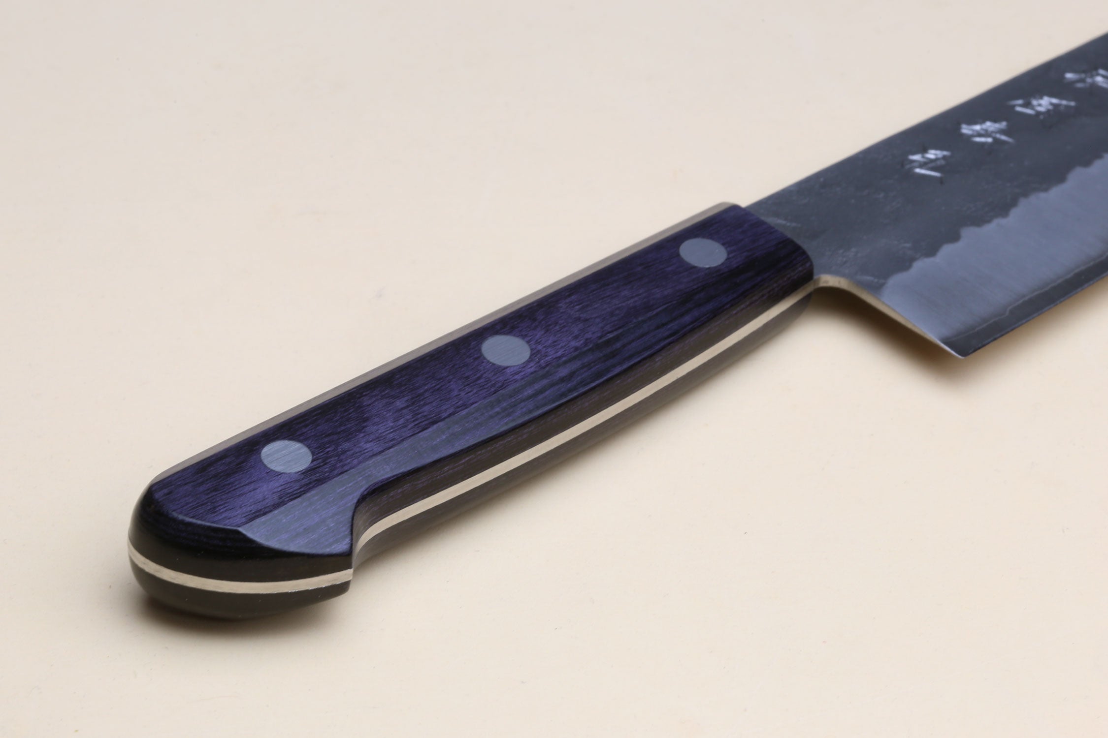 Santoku knife handle close-up, dark blue wood with silver rivets