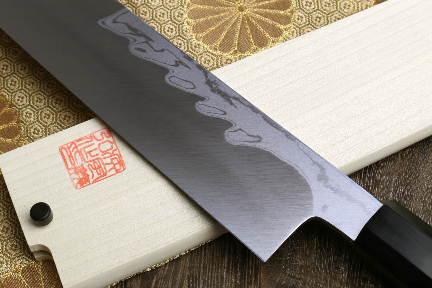Japanese chef knife with dark steel blade and wavy Damascus pattern, ebony handle