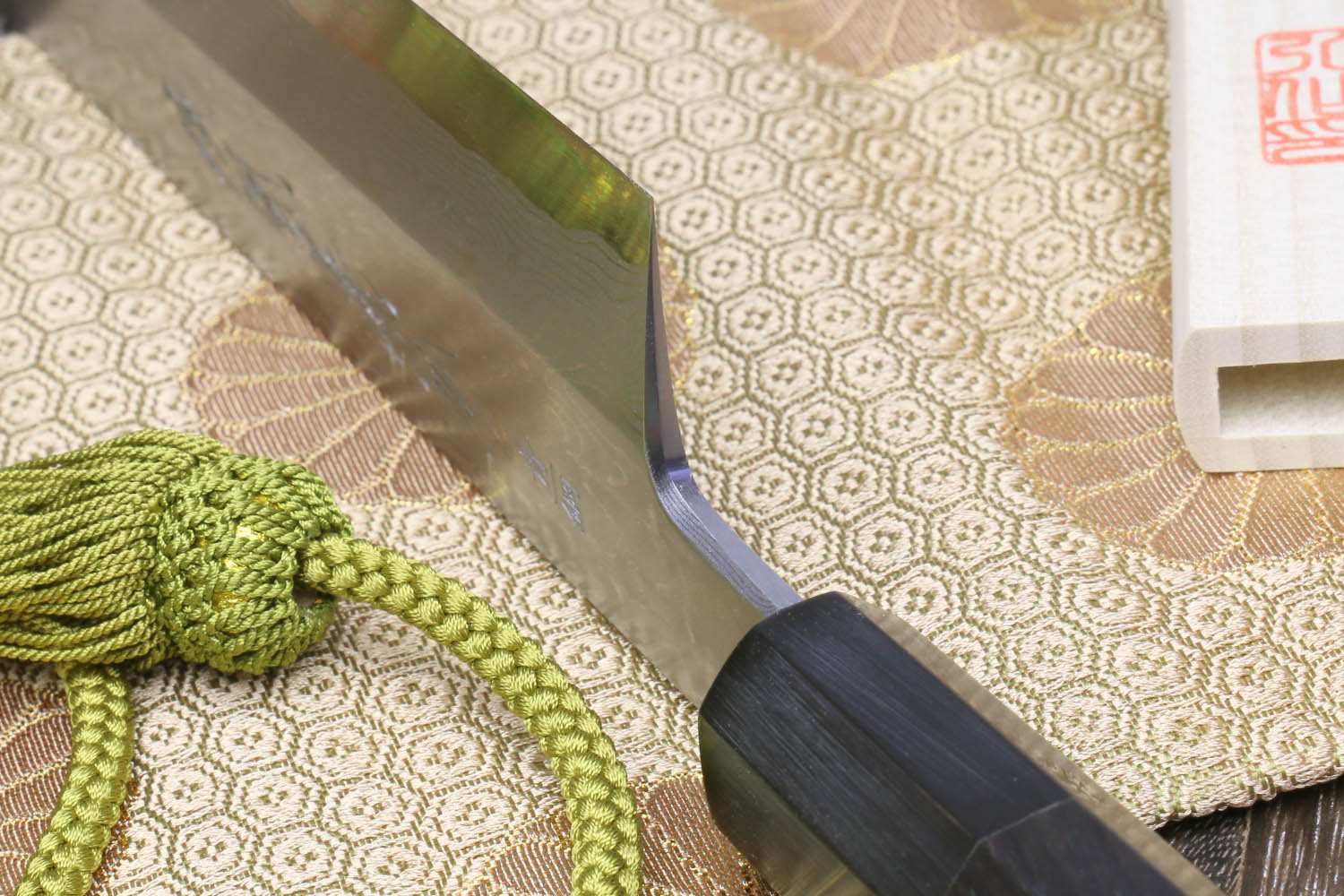 Japanese chef knife close-up: dark ebony handle and gray blade edge