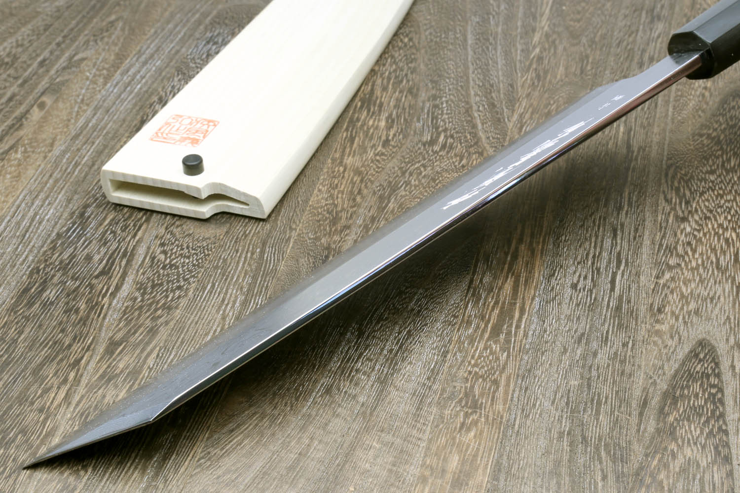 Kiritsuke chef knife with long gray steel blade and dark ebony wood handle