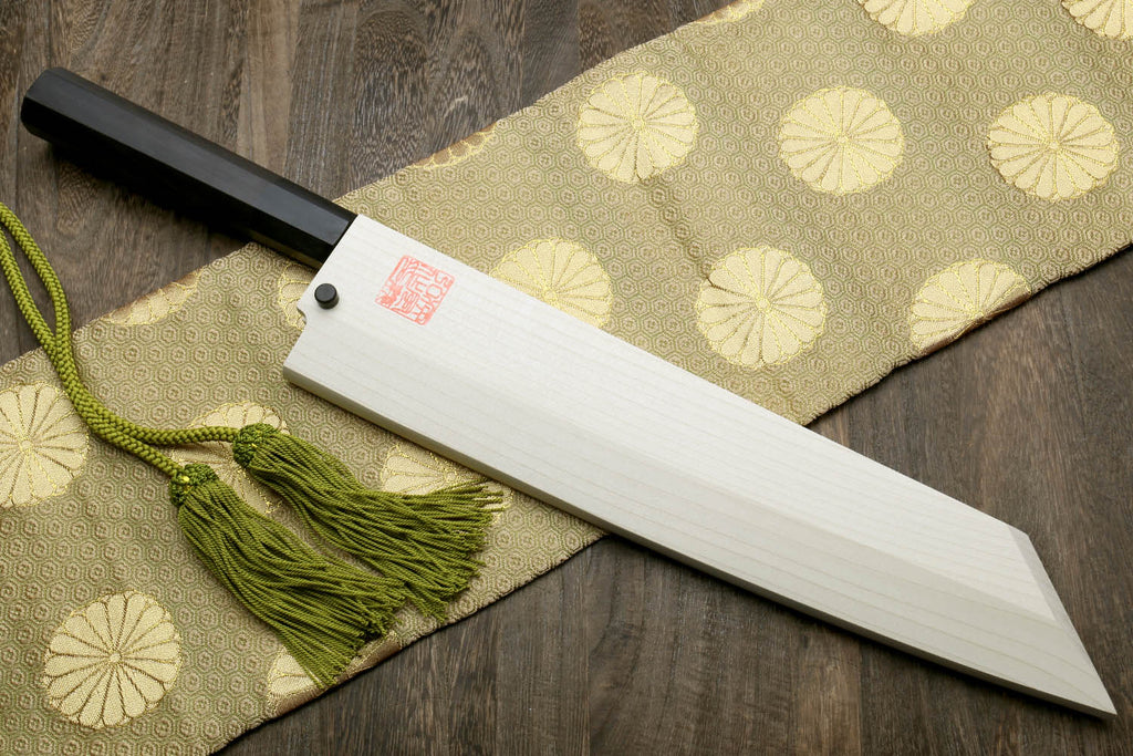 Japanese chef knife with dark ebony handle, white blade, and decorative green tassel