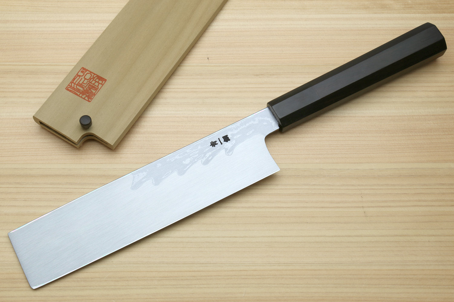 Japanese vegetable prep knife with long white damascus blade and black ebony handle