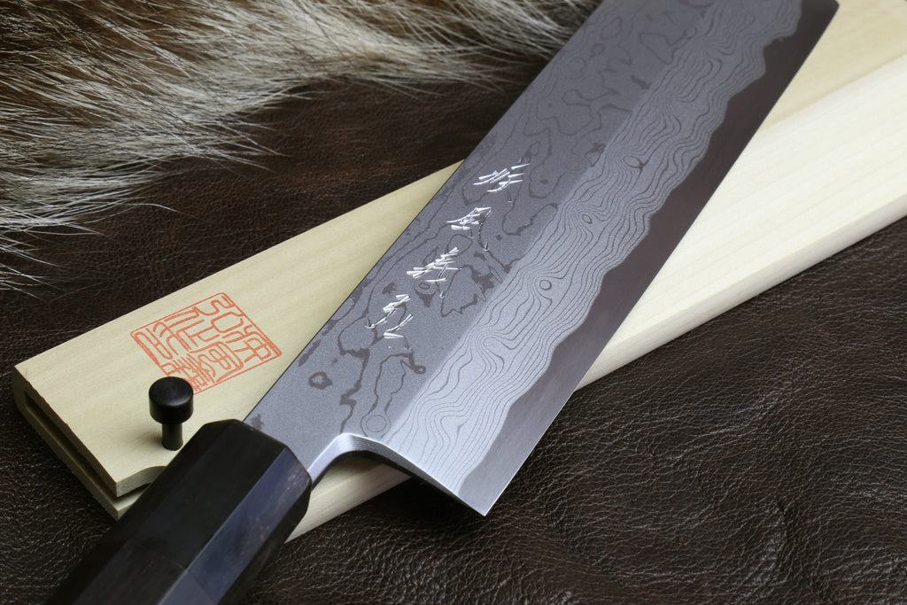 Japanese vegetable prep knife with etched damascus blade and ebony handle on leather