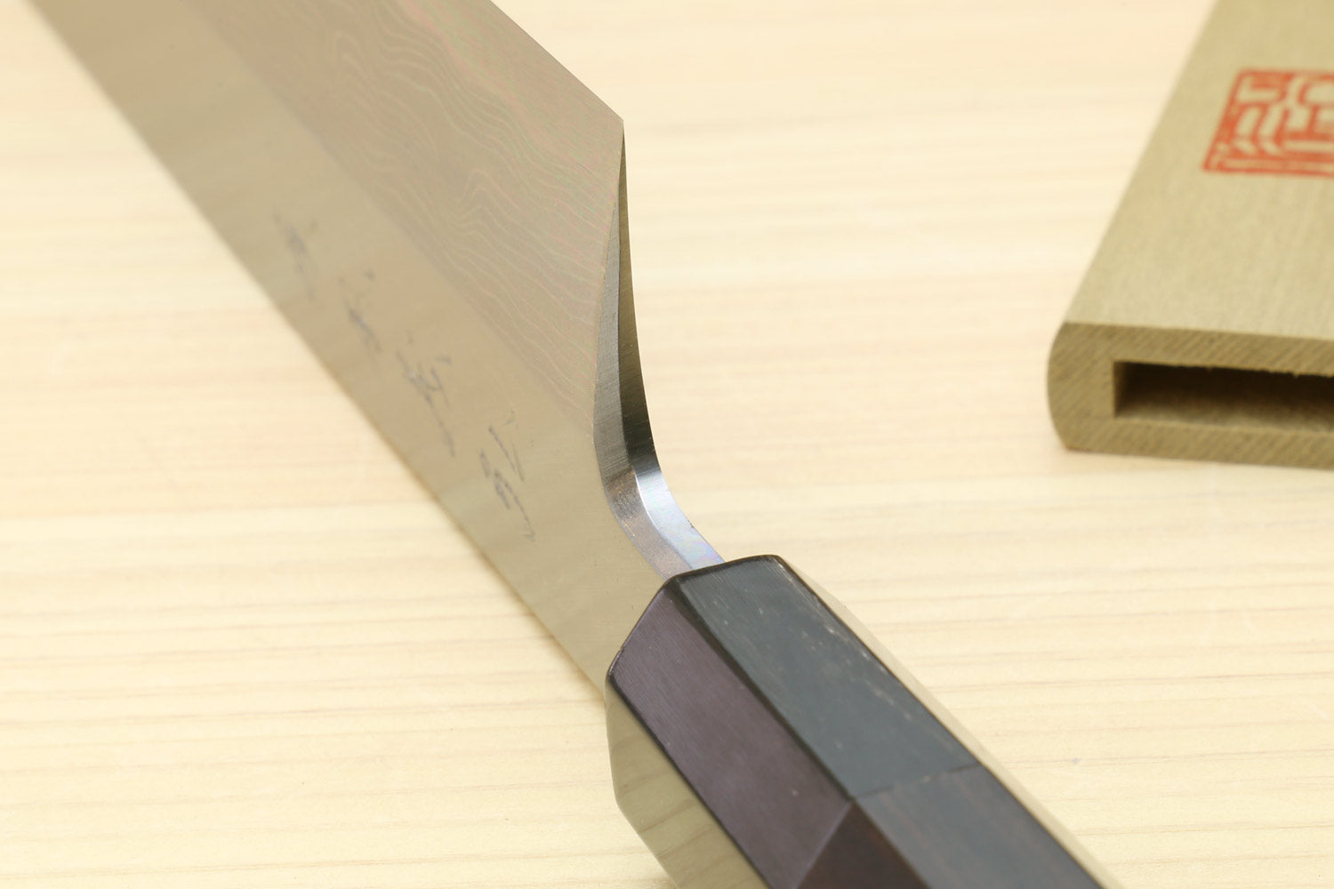 Japanese vegetable prep knife: close-up of curved blade edge and ebony handle