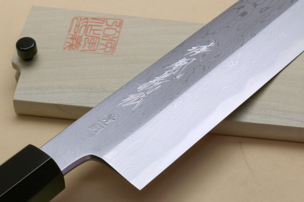 Japanese vegetable knife blade close-up with swirling damascus pattern and black handle