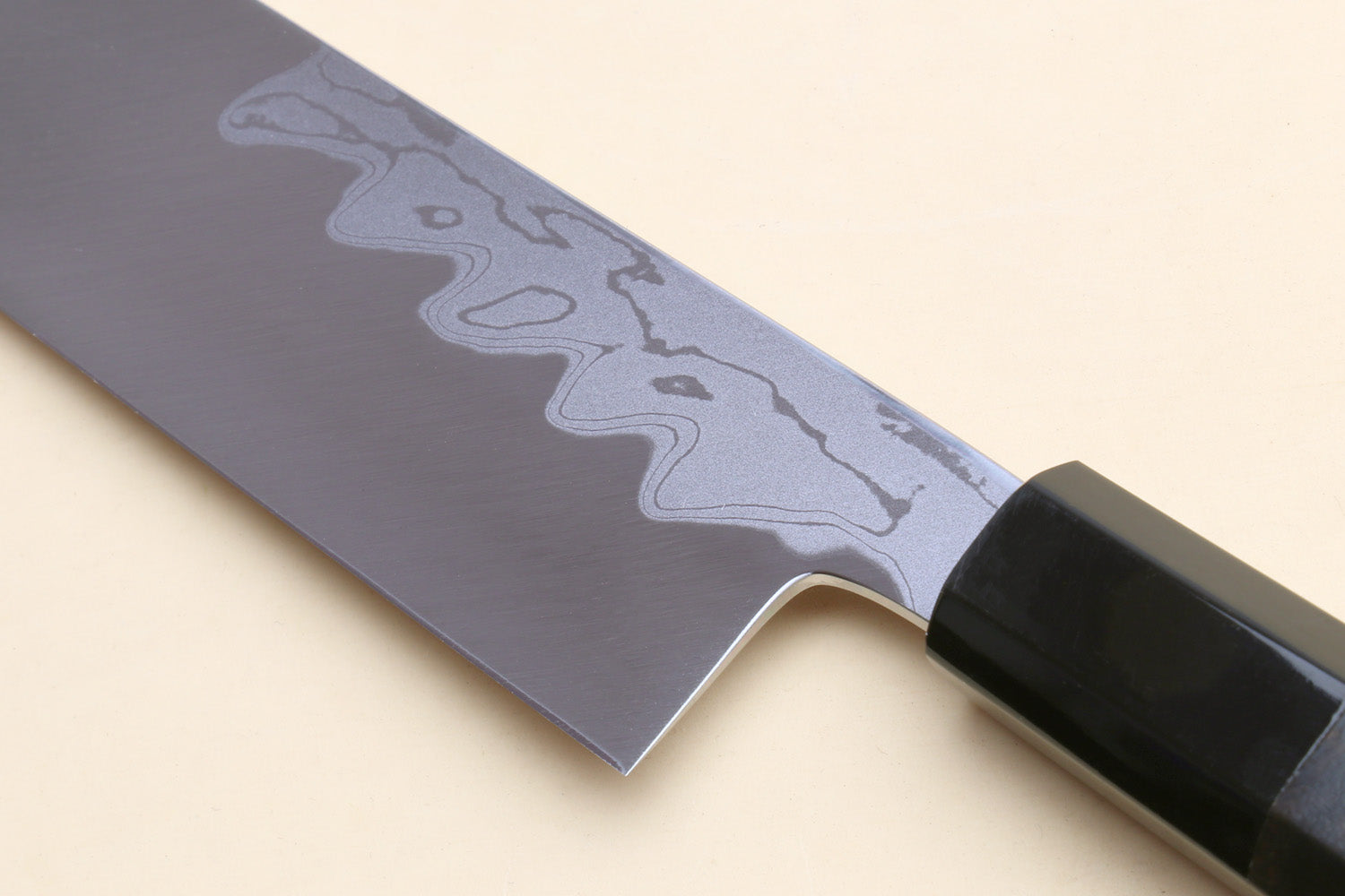 Japanese vegetable knife with pointed blade edge and black handle; damascus pattern visible