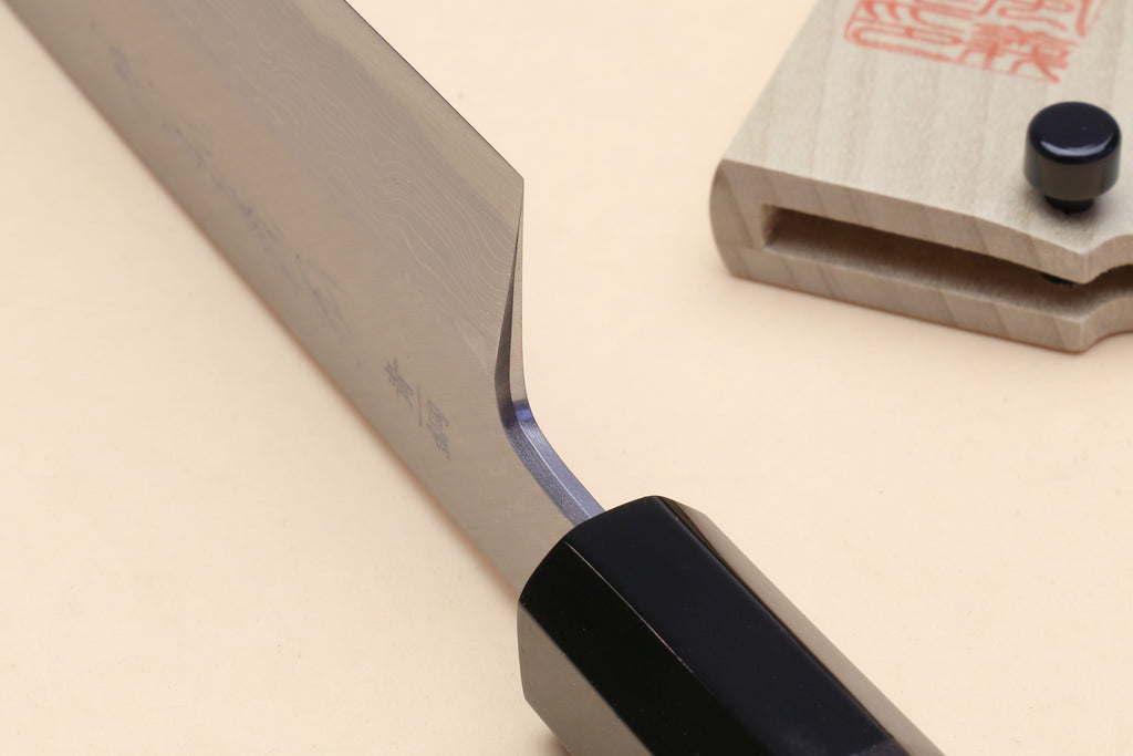 Japanese vegetable knife with curved blade near heel and black handle; wooden saya shown