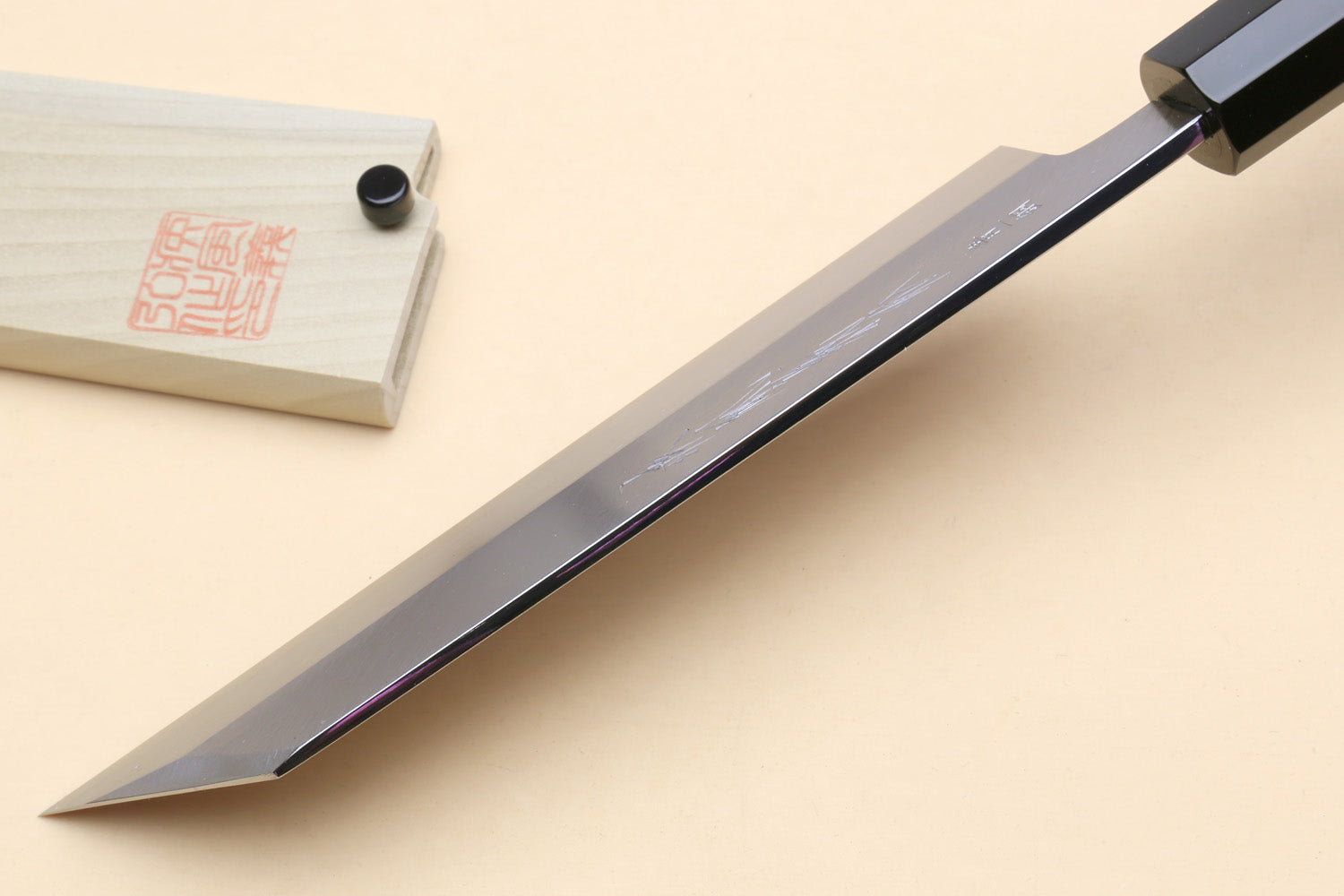 Japanese vegetable knife with long pointed blade and black handle; wooden saya on side