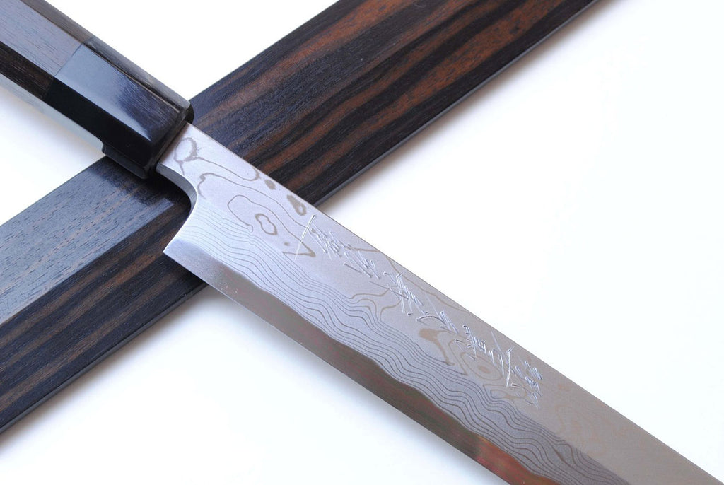 Japanese chef knife blade close-up with Damascus pattern and dark ebony handle