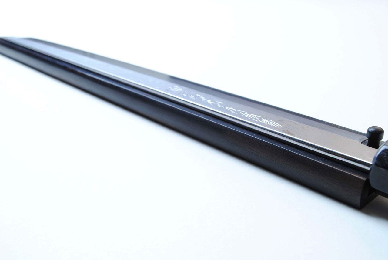 Japanese chef knife with dark ebony wood handle and engraved blade back, close-up