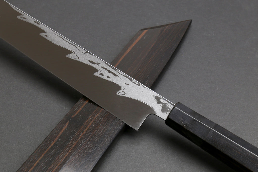 Japanese yanagi sushi knife with damascus blade and ebony handle, partial sheath visible