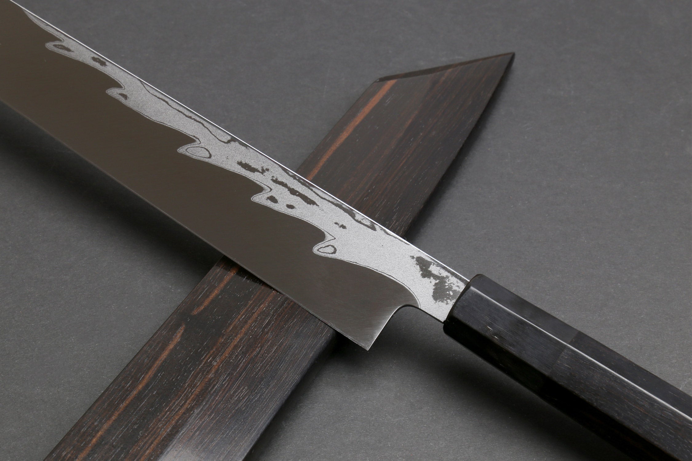 Japanese yanagi sushi knife with damascus blade and ebony handle, partial sheath visible